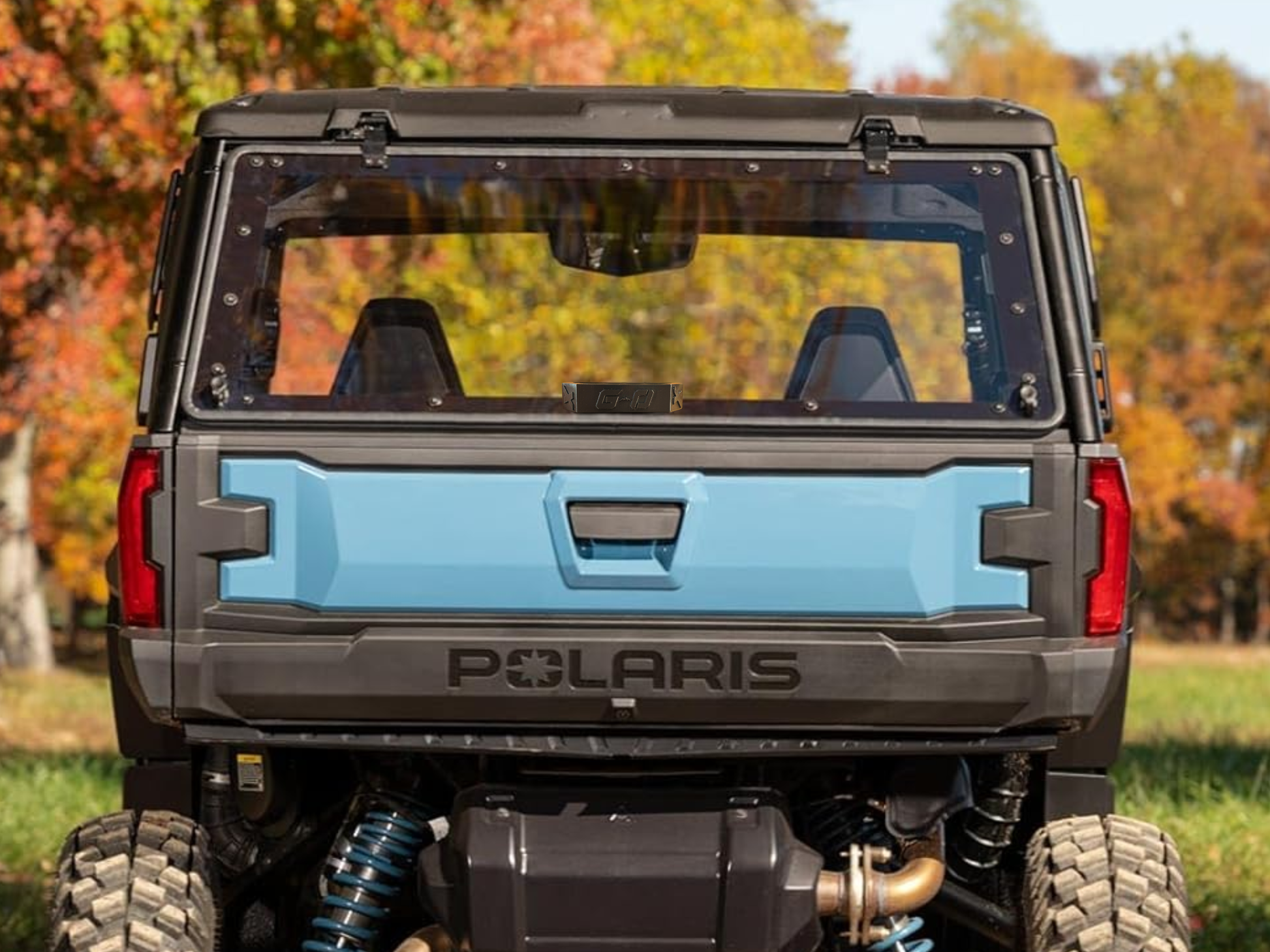 Polaris vehicle with a blue cargo bed in an outdoor setting with trees in the background