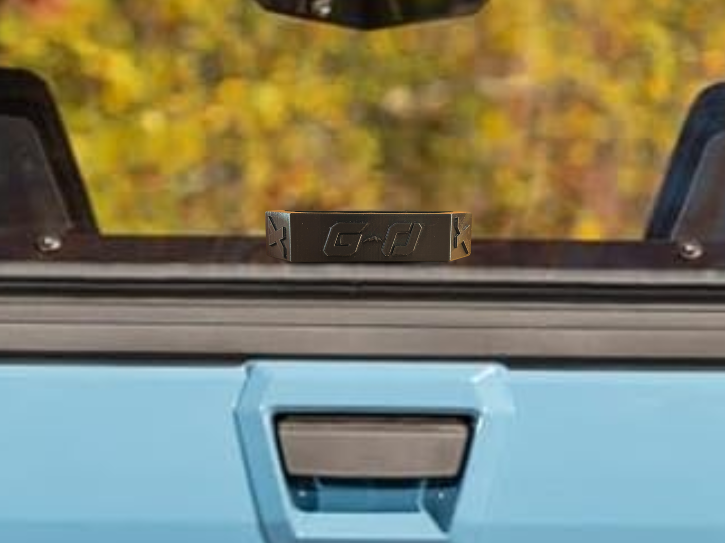 Close-up of a blue vehicle with a window and windshield wiper, blurred outdoor background